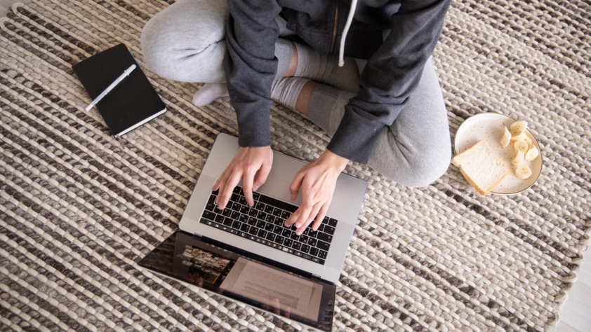 a person typing on his laptop on the ground