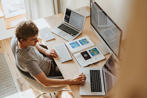 a man sitting in his office with laptops and monitors in front of him
