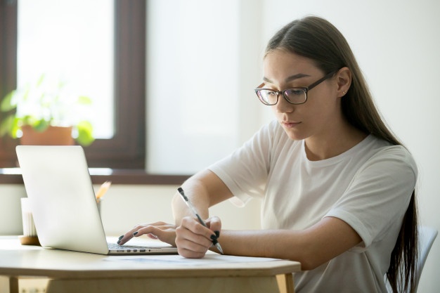 A woman typing and writing using both hands