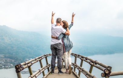 Two person standing at the edge kissing and throwing a rock sign in the air